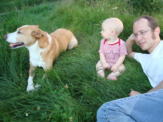 a dog, a baby boy, and a dad in the backyard